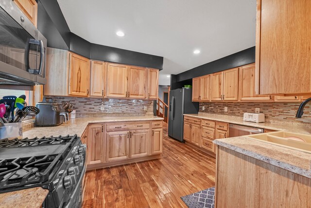 kitchen with tasteful backsplash, appliances with stainless steel finishes, light brown cabinetry, light hardwood / wood-style flooring, and sink