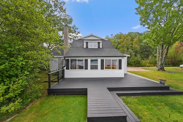 rear view of property featuring a wooden deck and a lawn