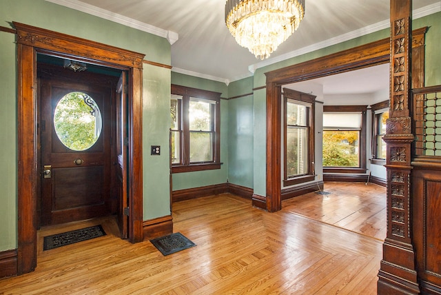 entryway featuring an inviting chandelier, ornamental molding, and light parquet flooring