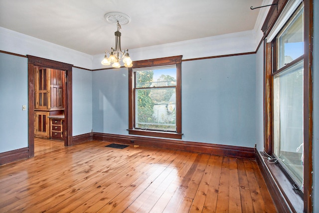 unfurnished room featuring ornamental molding, hardwood / wood-style floors, and a chandelier