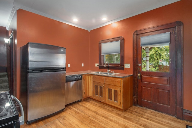 kitchen with light wood-type flooring, stone countertops, sink, crown molding, and stainless steel appliances