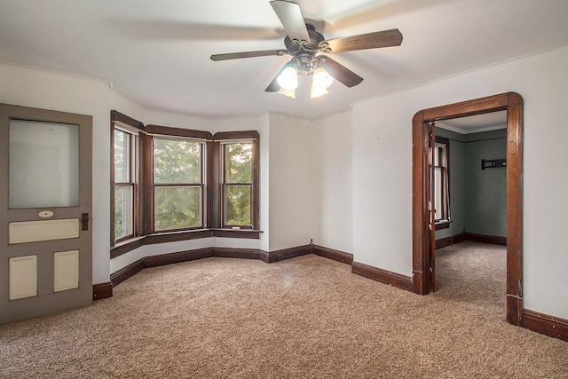 empty room featuring crown molding, carpet, and ceiling fan