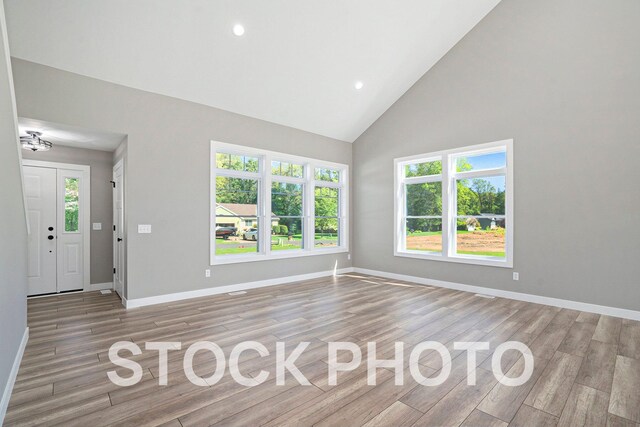 unfurnished living room featuring high vaulted ceiling and light hardwood / wood-style floors