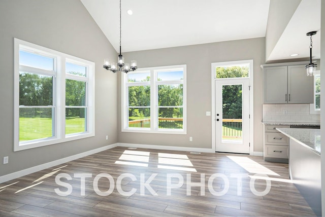 unfurnished dining area with vaulted ceiling, a healthy amount of sunlight, and light hardwood / wood-style flooring