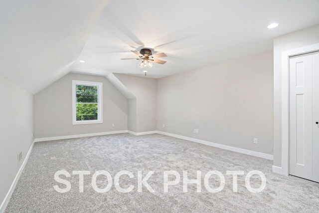 additional living space with vaulted ceiling, light carpet, and ceiling fan