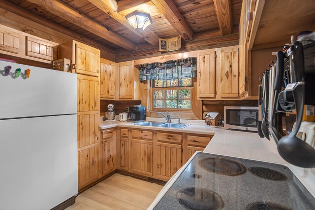 kitchen with sink, light wood-type flooring, wooden ceiling, white fridge, and beam ceiling