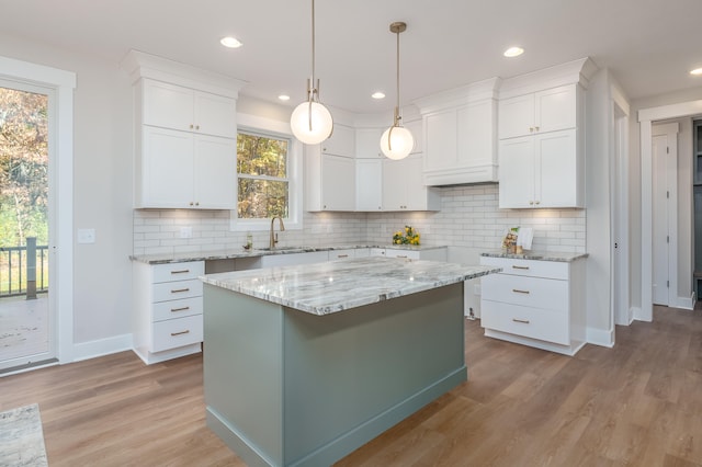 kitchen with a center island, white cabinetry, light wood-type flooring, and backsplash