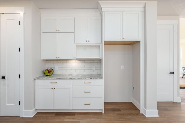 kitchen with light stone counters, tasteful backsplash, wood-type flooring, and white cabinets