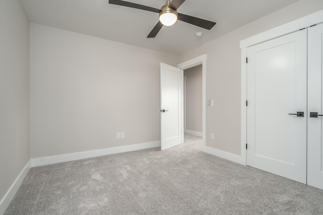 unfurnished bedroom featuring light colored carpet, a closet, and ceiling fan