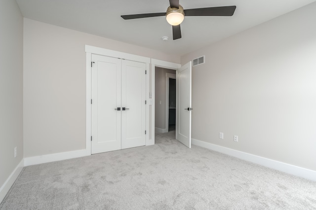 unfurnished bedroom with a closet, light colored carpet, and ceiling fan