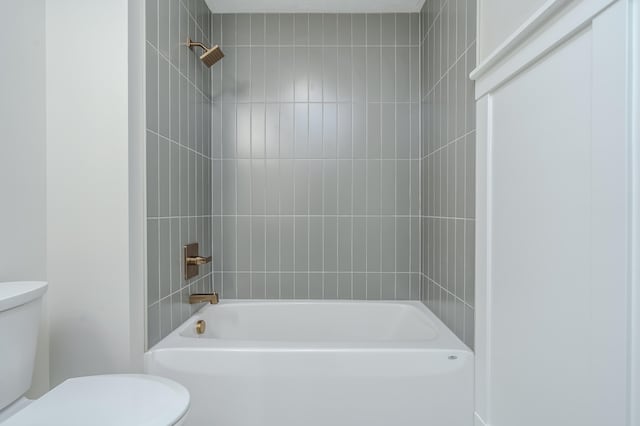 bathroom featuring tiled shower / bath combo and toilet