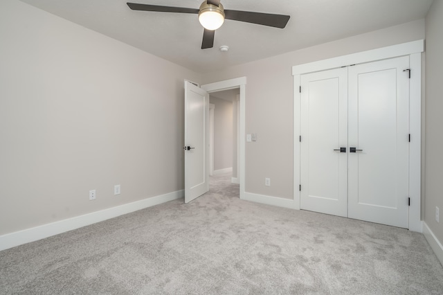 unfurnished bedroom featuring a closet, light colored carpet, and ceiling fan