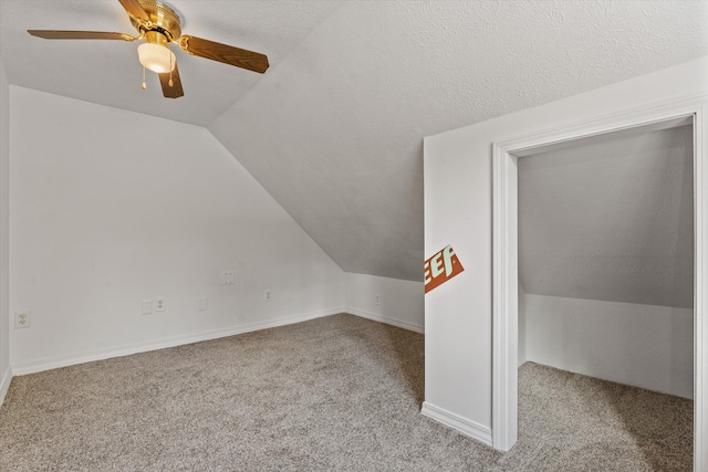 additional living space with vaulted ceiling, light carpet, a textured ceiling, and ceiling fan