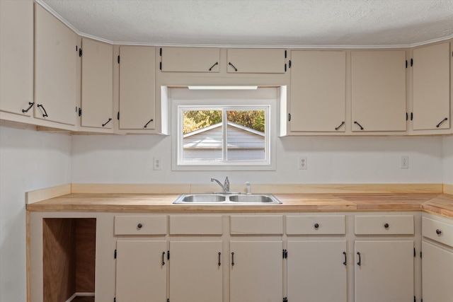 kitchen with a textured ceiling, butcher block counters, and sink