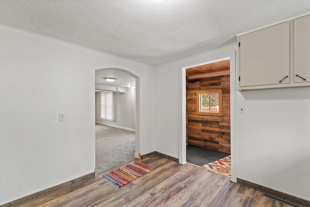 spare room with a wealth of natural light, wooden walls, and dark hardwood / wood-style floors