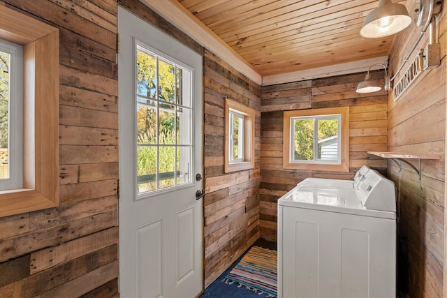 clothes washing area with washer and dryer, wooden ceiling, and wood walls