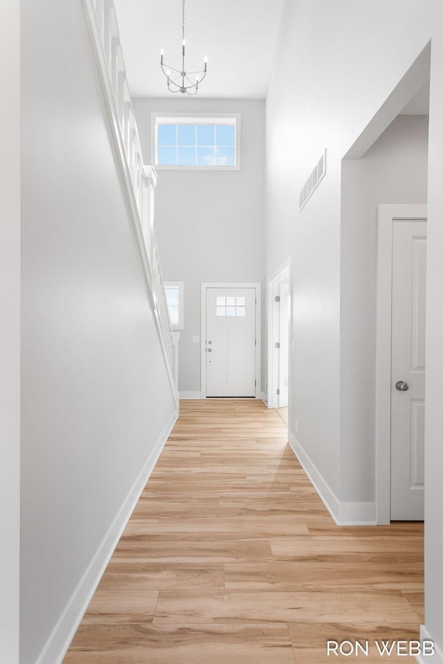 entryway featuring a towering ceiling, a notable chandelier, and light hardwood / wood-style floors