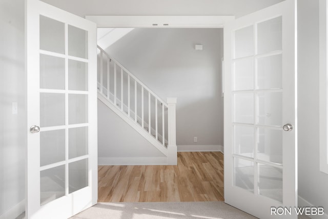 stairway with french doors and hardwood / wood-style flooring