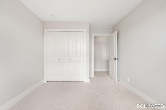 unfurnished bedroom with light carpet and a closet