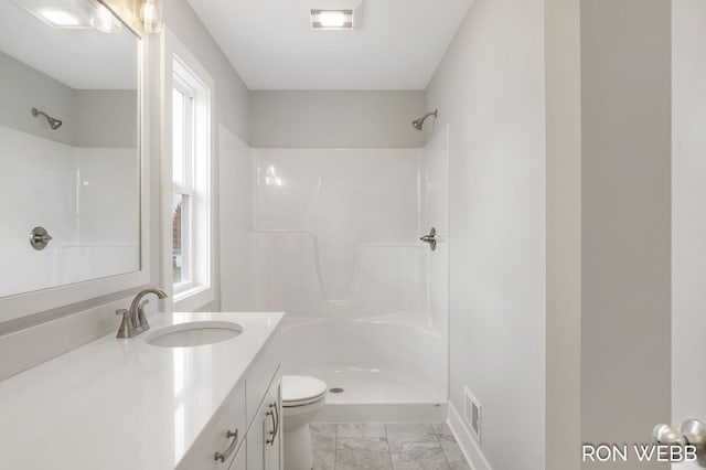 bathroom featuring vanity, walk in shower, and toilet