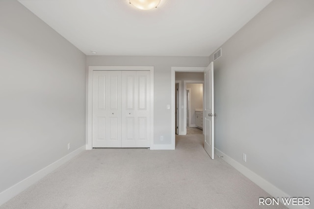 unfurnished bedroom with light colored carpet and a closet