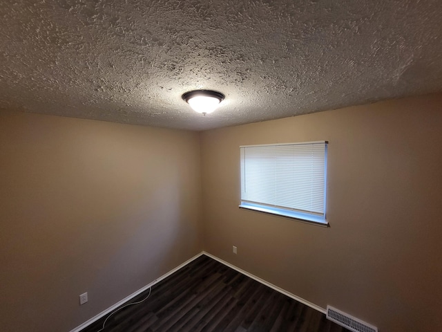 empty room featuring a textured ceiling and dark hardwood / wood-style flooring