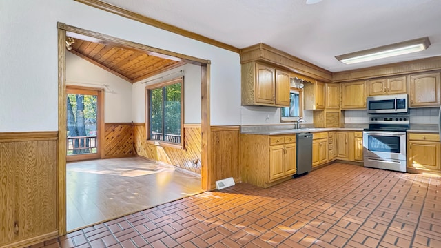 kitchen featuring tasteful backsplash, vaulted ceiling, wood walls, crown molding, and stainless steel appliances