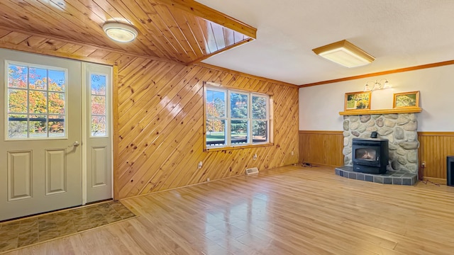 entrance foyer featuring wooden walls, a wood stove, and plenty of natural light