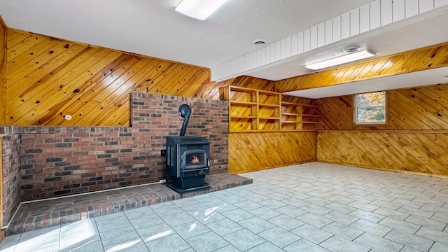 unfurnished living room with built in features, a wood stove, and wood walls