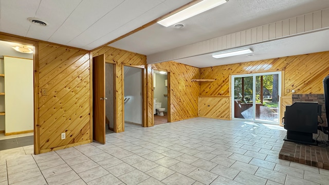 unfurnished living room with a wood stove and wood walls