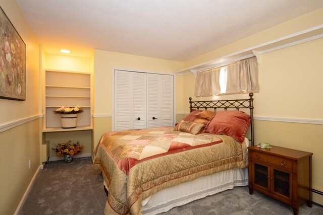 bedroom featuring baseboard heating, dark colored carpet, and a closet