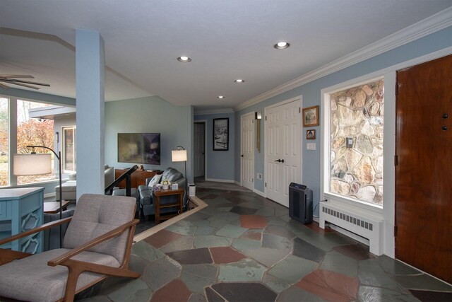 foyer with ornamental molding, radiator heating unit, and ceiling fan