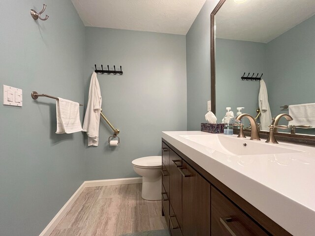 bathroom with toilet, a textured ceiling, vanity, and wood-type flooring