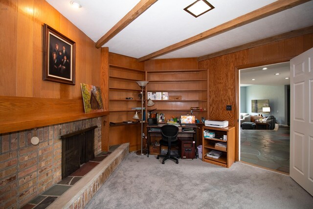 carpeted office space featuring beam ceiling, a fireplace, and wood walls