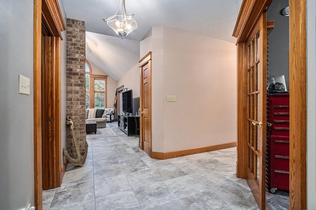 corridor with lofted ceiling and an inviting chandelier