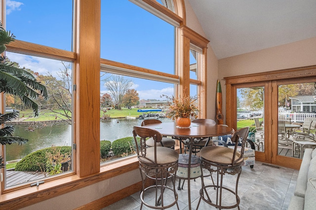 sunroom / solarium featuring a healthy amount of sunlight, a water view, and vaulted ceiling