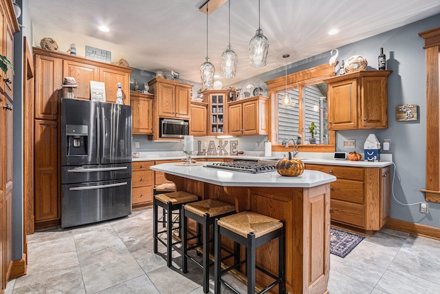 kitchen with appliances with stainless steel finishes, sink, a kitchen bar, a center island, and hanging light fixtures