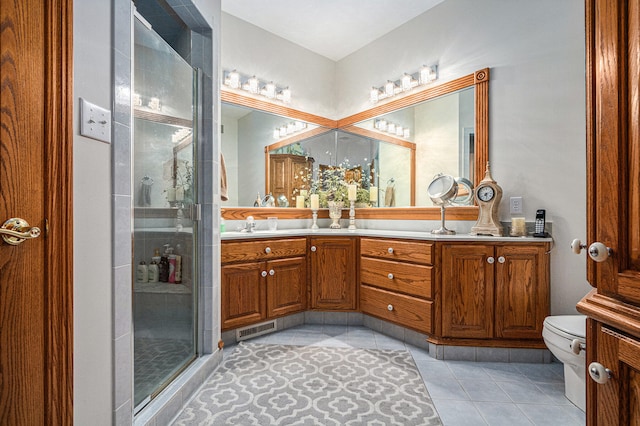 bathroom with vanity, toilet, a shower with shower door, and tile patterned flooring