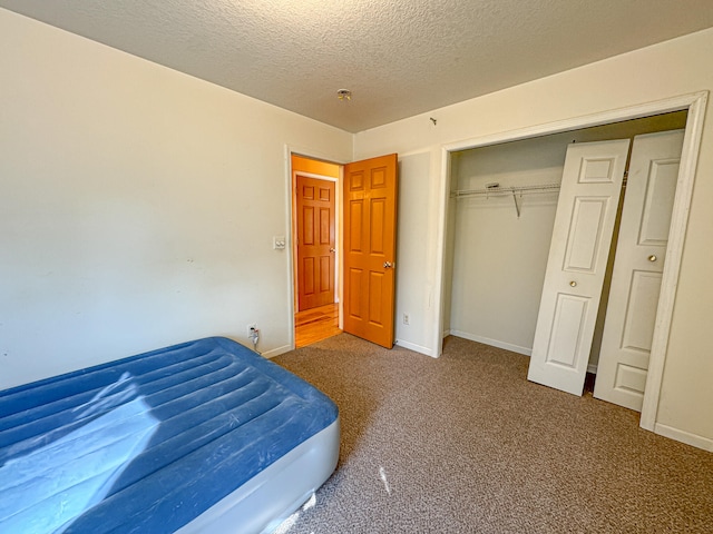 bedroom with a closet, a textured ceiling, and carpet