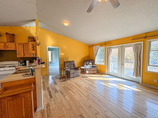 living room featuring lofted ceiling, light hardwood / wood-style flooring, a textured ceiling, and ceiling fan