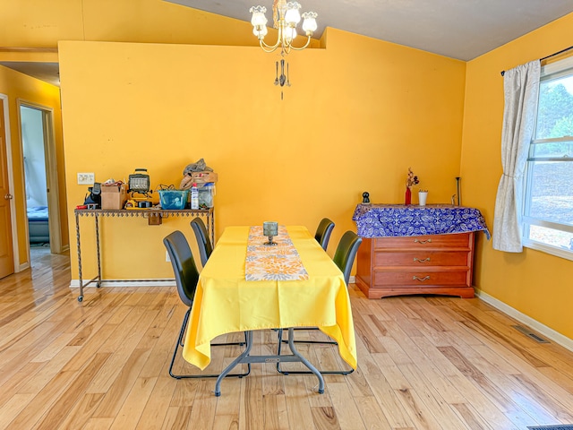 dining space featuring light hardwood / wood-style flooring, lofted ceiling, and an inviting chandelier