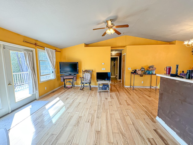 sitting room with light hardwood / wood-style flooring, vaulted ceiling, and ceiling fan with notable chandelier