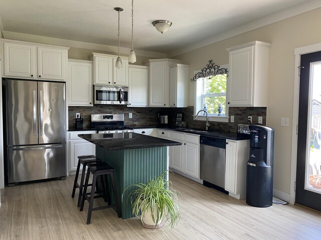 kitchen featuring appliances with stainless steel finishes, sink, a kitchen island, white cabinets, and decorative backsplash