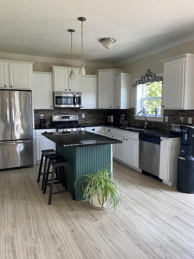 kitchen with white cabinets, tasteful backsplash, a kitchen island, appliances with stainless steel finishes, and sink