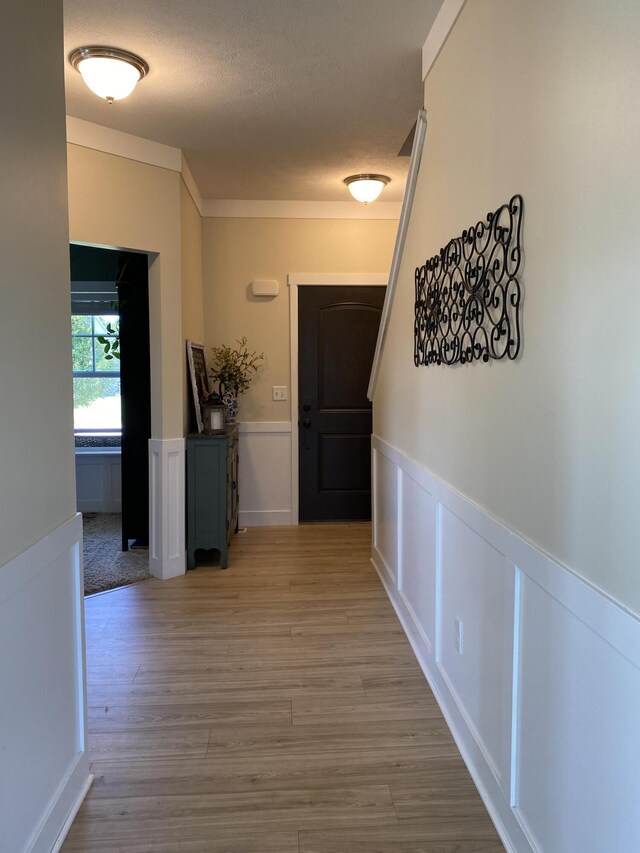 hall with a textured ceiling and light wood-type flooring