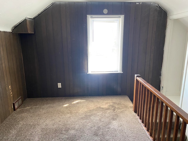 additional living space featuring vaulted ceiling, carpet floors, and wood walls