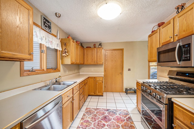 kitchen featuring sink, light tile patterned flooring, a textured ceiling, stainless steel appliances, and decorative light fixtures