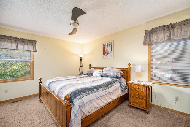 bedroom featuring a textured ceiling, light colored carpet, and ceiling fan