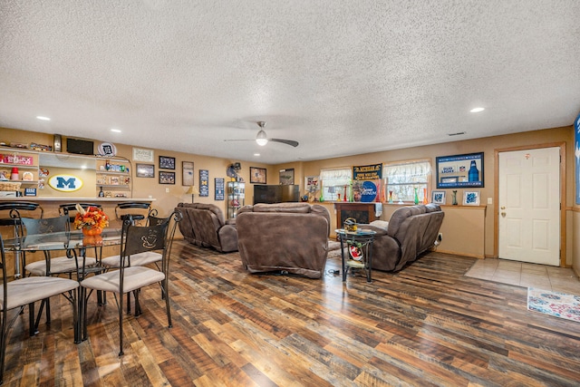 living room featuring a textured ceiling, wood-type flooring, and ceiling fan