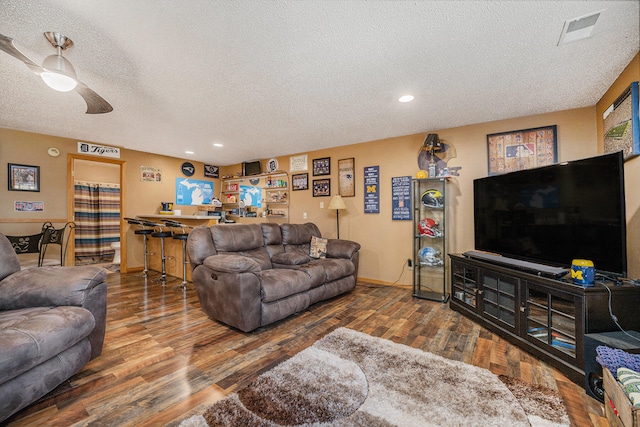 living room featuring a textured ceiling, wood-type flooring, and ceiling fan